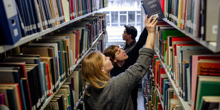 Bücherrecherche in der Bibliothek Studierende suchen nach Büchern in Bücherregalen in der Bibliothek.